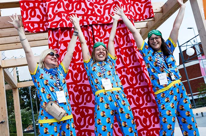 three women wearing blue ikea meatball pyjamas pose next to a life size red pyjamas
