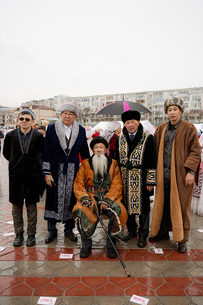 a group of men dressed in kazakh clothing with accents of red white and brown