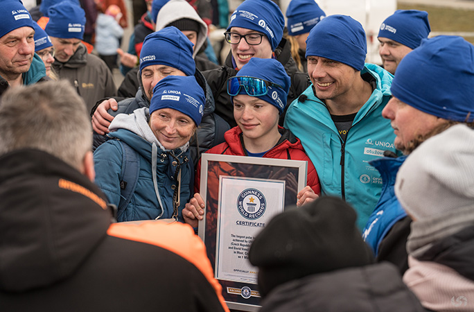 david vencl smiles with a child and other participants while holding the guinness world records certificate