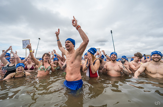a man smiling wide and arms in the air with participants beside him in lake most