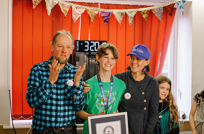 micah smiling with his parents while holding a guinness world records certificate