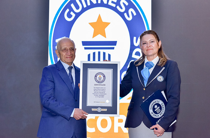 faig stands in front of guinness world records record holder logo and smiles holding his certificate