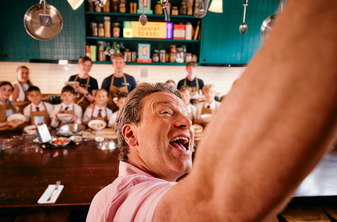 jamie oliver wearing a pink shirt takes a selfie with children