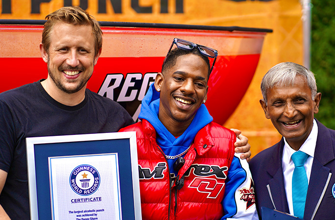 three men stand next together smiling with one holding a guinness world reords certificate