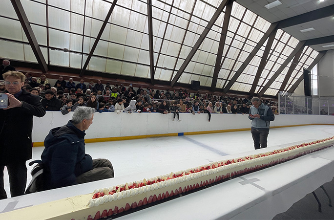members of the public stand next to the longest strawberry cake