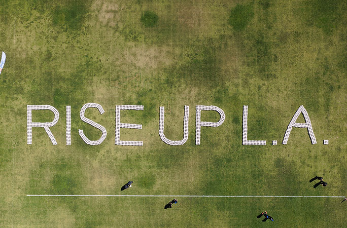 soccer balls arranged on the green grass spelling out rise up la