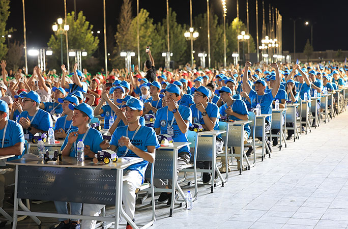 students seated in rows of chairs dressed in blue cheering