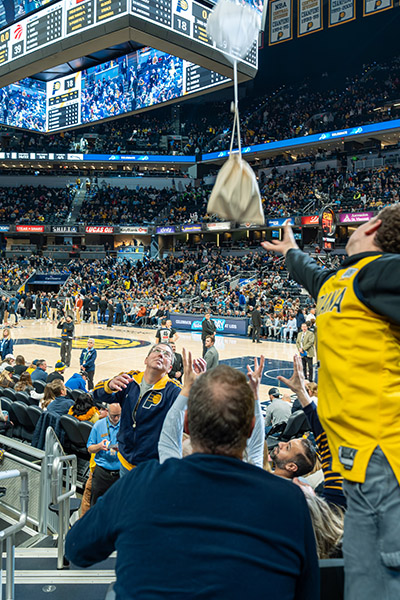 a man dressed in a yellow jersey reaches out to a brown bag