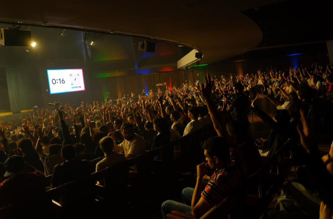 Audience in the dark with their hands in the air