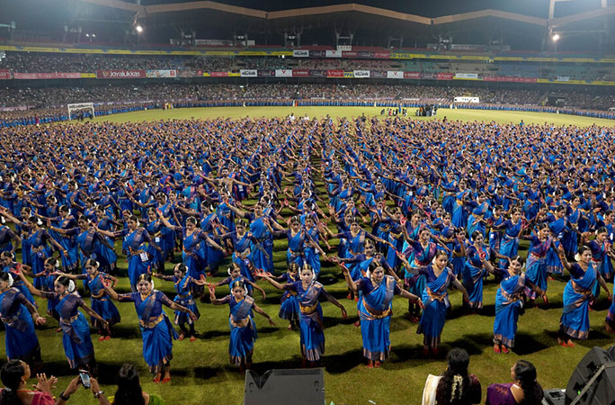 a row of women wearing blue saris perform a dance