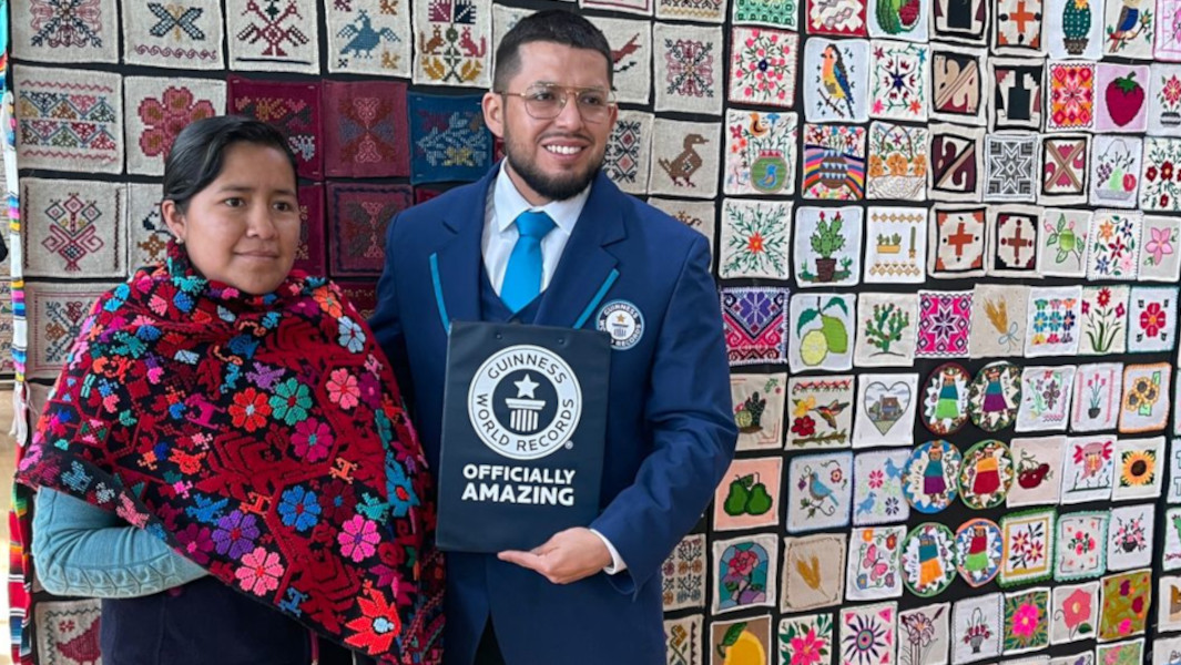 Alfredo and embroiderer in front of embroidery display