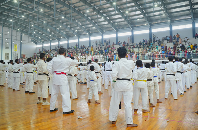people in traditional white karate practice outfits punch air