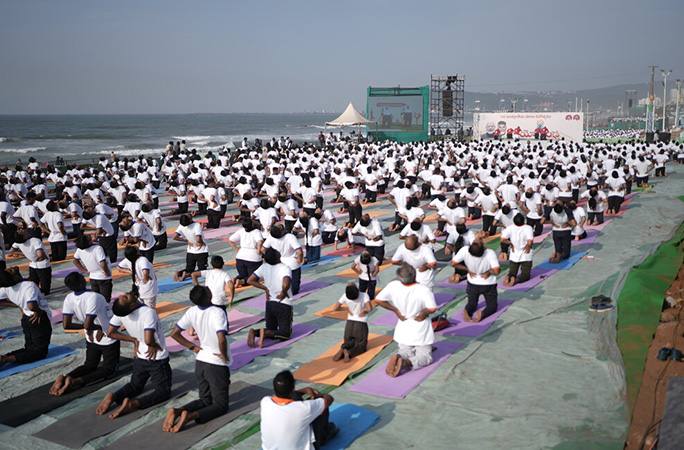 people in rows wearing white perform yoga poses