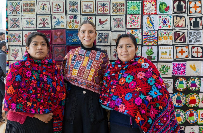 Three women posing with the artwork