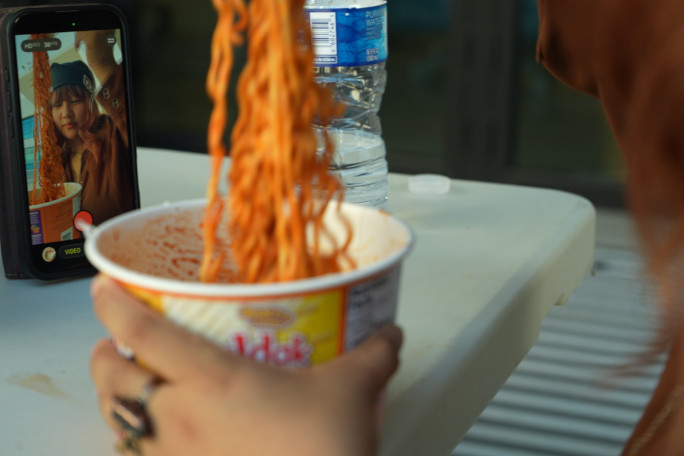 A woman filming herself eating Buldak ramen