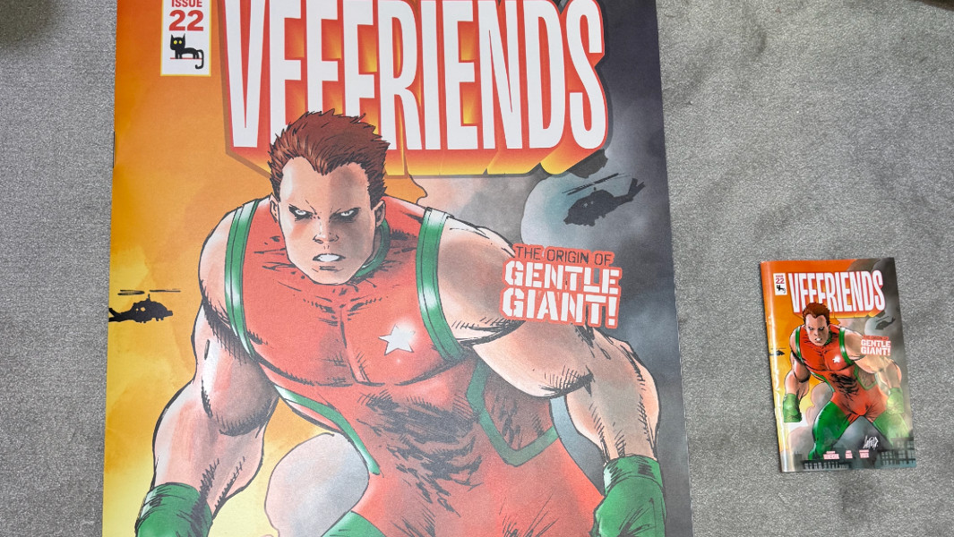 Split image of the large comic next to a small comic, and a VeeFriends employee setting up the comic