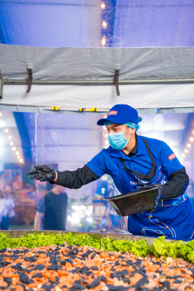 A man sprinkling seasoning on the fiambre