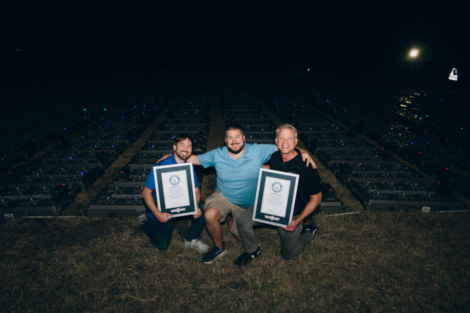 Three organizers holding the certificates in front of the drones