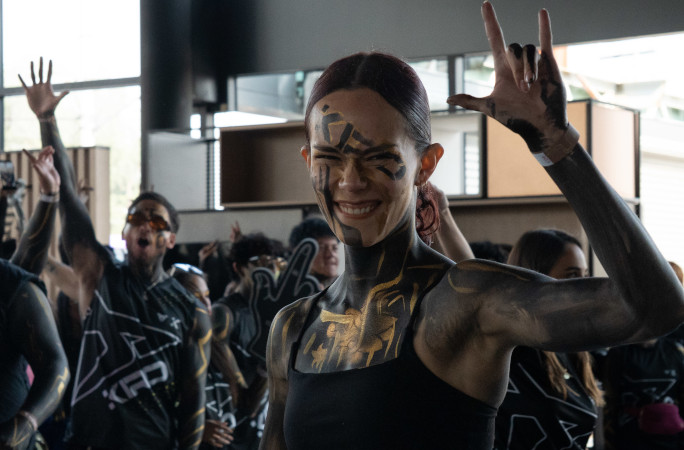 A woman covered in body paint giving a rocker sign