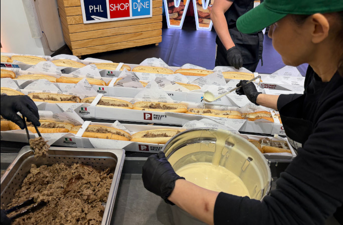 Chefs pouring cheese on the sandwiches