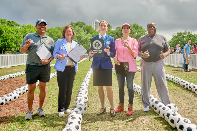 Adjudicator and event organizers standing in front of the soccer balls