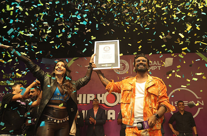 a man and a woman hold a guinness world records certificate while multi coloured confetti rains on them