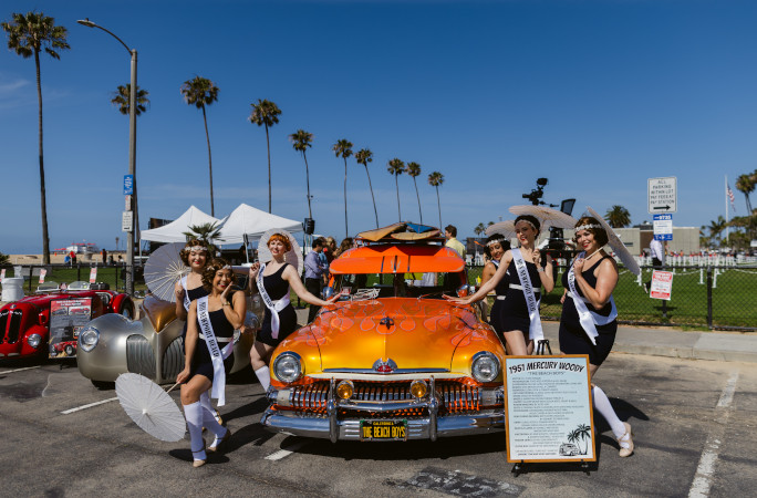 Dancers posing next to an orange vintage car