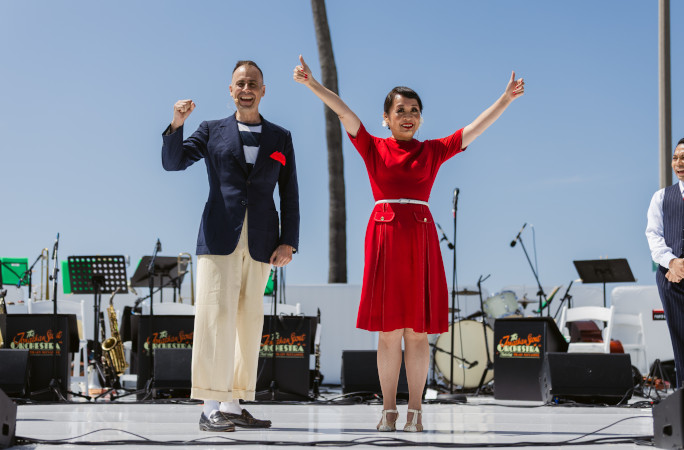 Instructors onstage in a red dress and blue suit