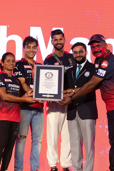 a guinness world records certificate is presented to two men wearing red cricket jerseys