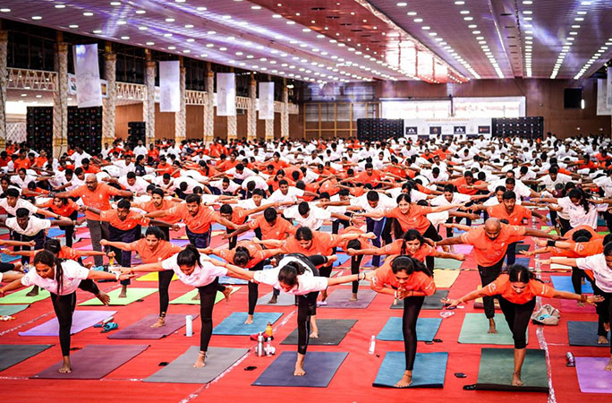 several people in red shirts take part in a synchronized yoga pose