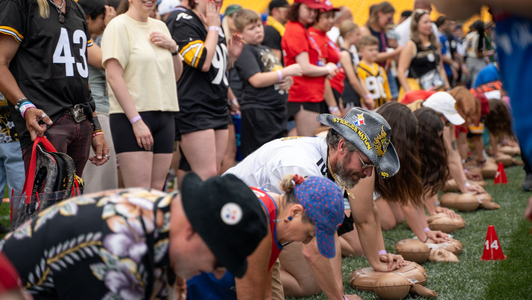 Closeup of Steelers fans completing chest compressions while on the field