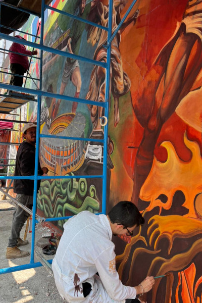 Workers painting an orange section of the mural