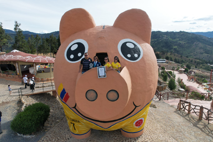 A group standing inside the nose of the piggy bank with event certificate