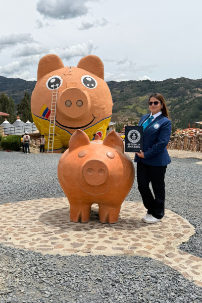 Adjudicator with certificate next to a small piggy bank and the largest piggy bank