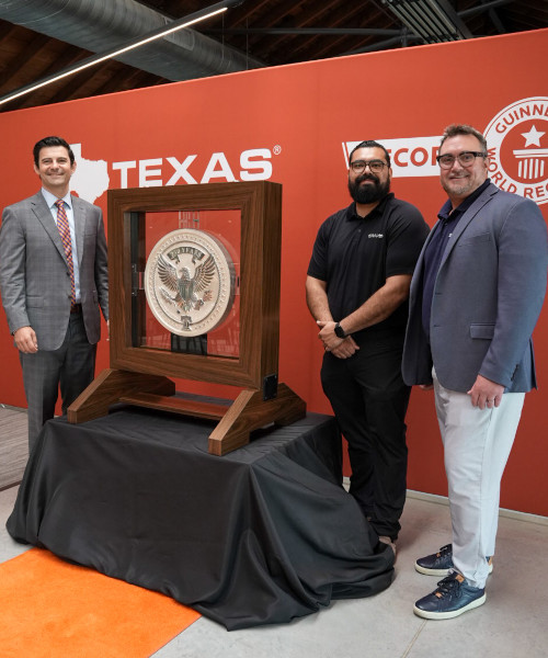 Three team members standing next to the coin