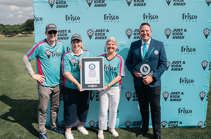 group of people stand in a line wearing blue jerseys and one is holding a guinness world records certificate