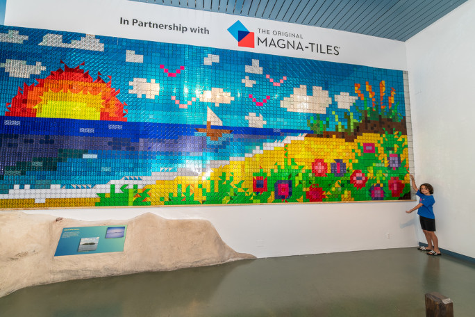 A kid standing next to the mosaic