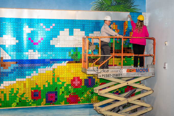 A man and a woman assembling the mosaic while on a crane