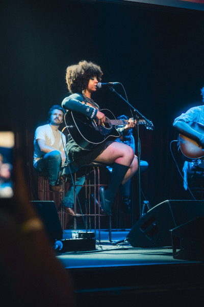 A woman singing onstage with a guitar