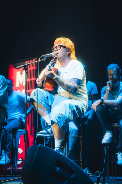 A musician with orange hair singing onstage
