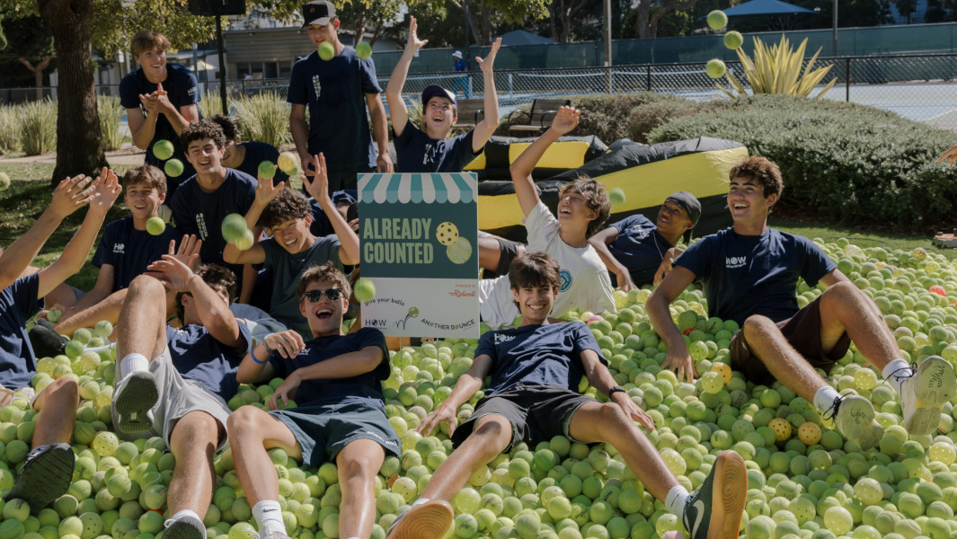 Teens from Another Bounce celebrating in a pile of collected sports balls at the event