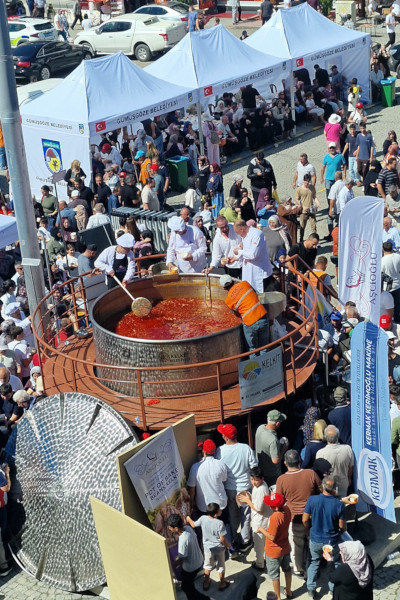 Vertical shot of the chefs stirring the beans in front of a crowd