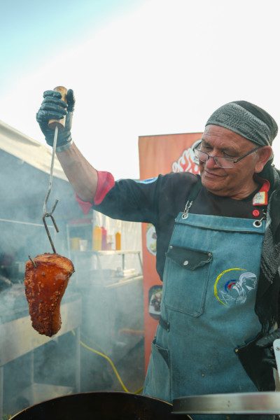 A man holding up a piece of grilled meat