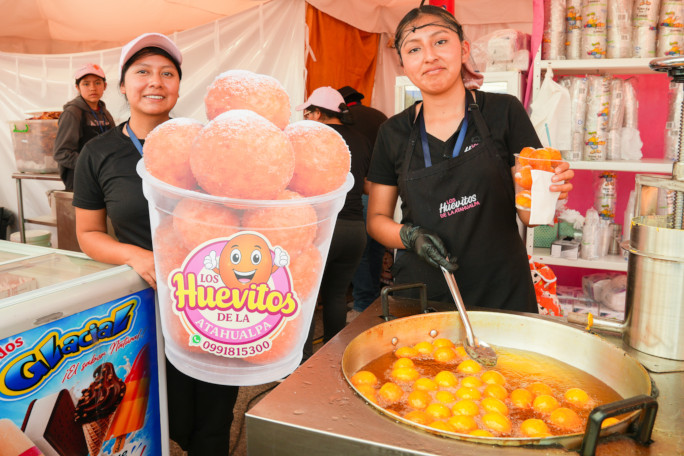 Two girls frying donuts