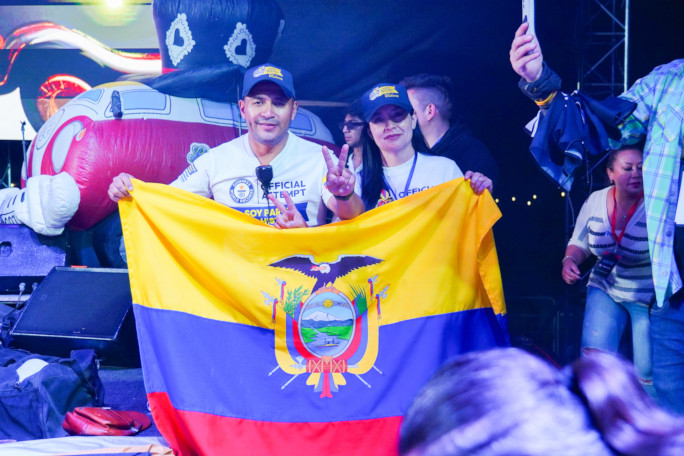 Two people holding the Ecuadorian flag onstage