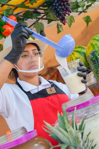 A woman wearing PPE and pouring a drink into a cup