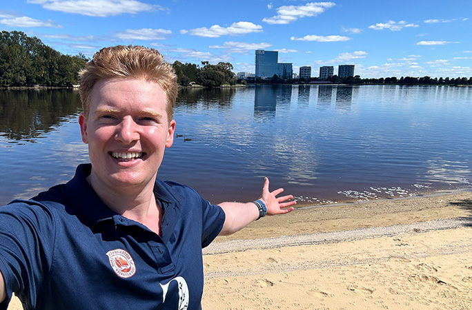 man smiles gesturing to the backdrop behind him