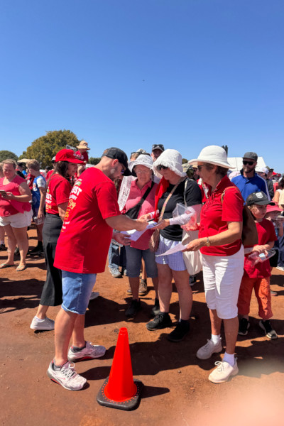 A steward checking in participants in red shirts