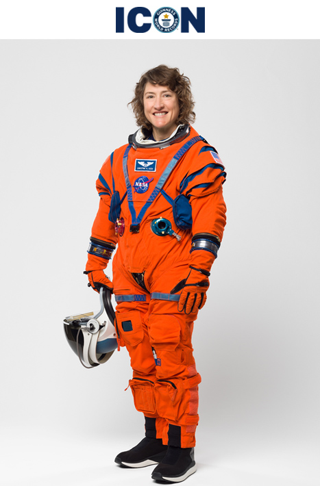 Christina wearing red spacesuit holding helmet in hand against white background