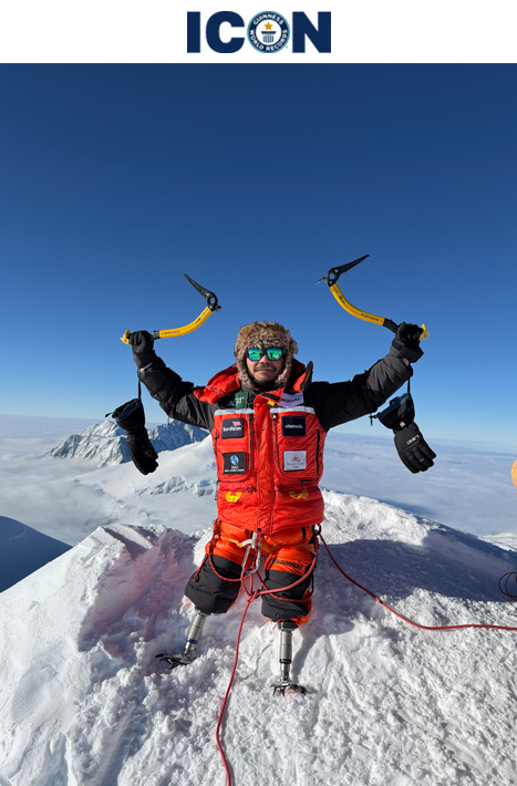 Hari on mountain holding sherpa tools triumphantly above head